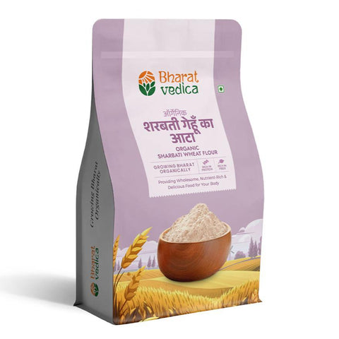 A purple and white packet of Bharat Vedica brand Organic Sharbati Wheat Flour, with text in both Hindi and English. The packet features the brand logo at the top and an image of wheat grains at the bottom. The text on the packet reads "ऑर्गेनिक शरबती गेहूँ का आटा ORGANIC SHARBATI WHEAT FLOUR" and "Providing Wholesome, Nutrient-Rich & Delicious Food for Your Body".