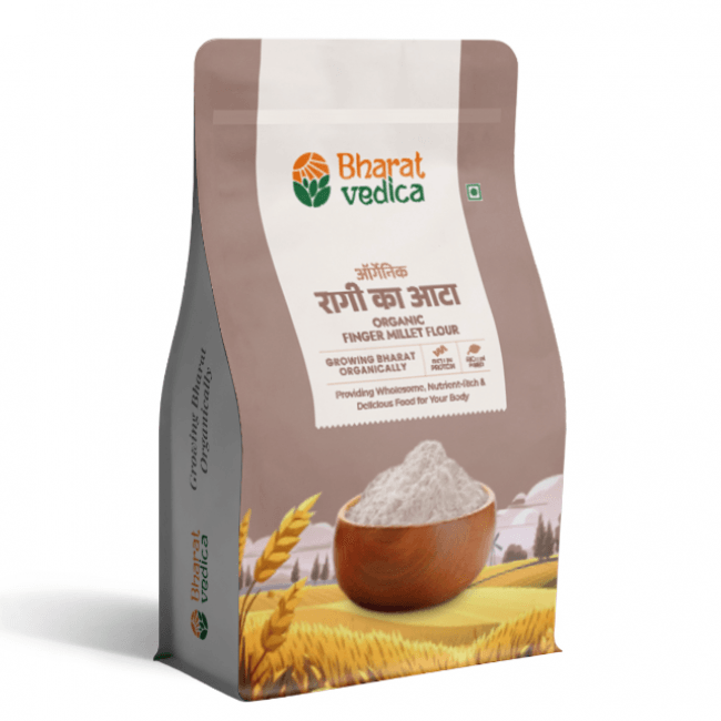 A brown and white packet of Bharat Vedica brand Organic Finger Millet Flour, with text in both Hindi and English. The packet features the brand logo at the top and an image of finger millet grains at the bottom. The text on the packet reads "ऑर्गेनिक रागी का आटा ORGANIC FINGER MILLET FLOUR" and "Providing Wholesome, Nutrient-Rich & Delicious Food for Your Body".
