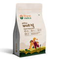 A white packet of Bharat Vedica brand Organic Khapli Wheat, with text in both Hindi and English. The packet features the brand logo at the top and an illustration of a farmer and a woman in a field of wheat at the bottom. The text on the packet reads "ऑर्गेनिक खपली गेहूँ Organic Khapli Wheat" and "100% ORGANIC GROWING BHARAT ORGANICALLY".