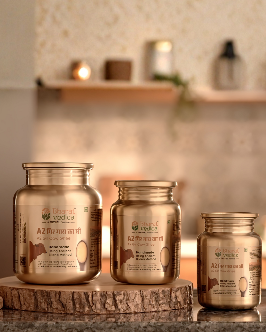 Three stainless steel jars of a2 gir cow ghee by Bharat Vedica on a wooden stand against a blurred background
